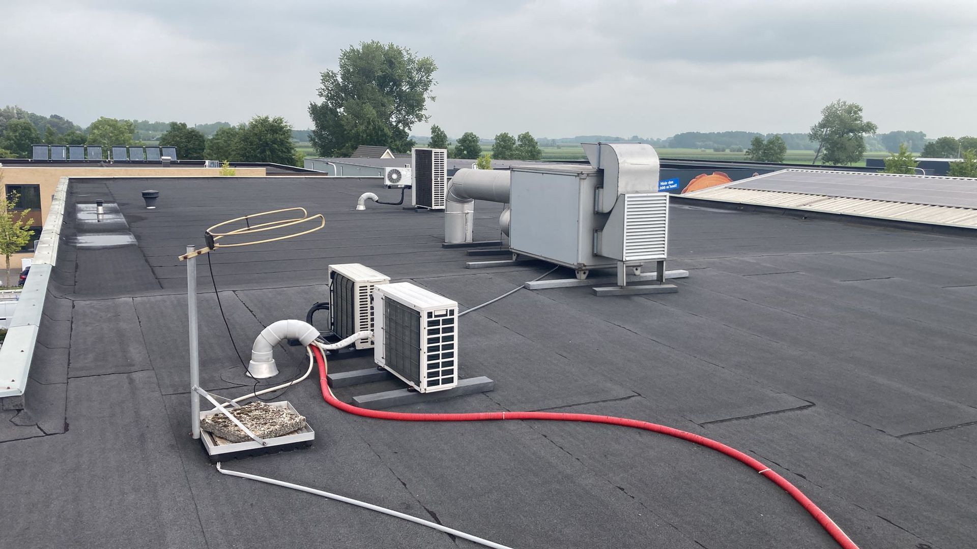 Dak met airconditioningunits en andere apparatuur tegen een bewolkte hemel.