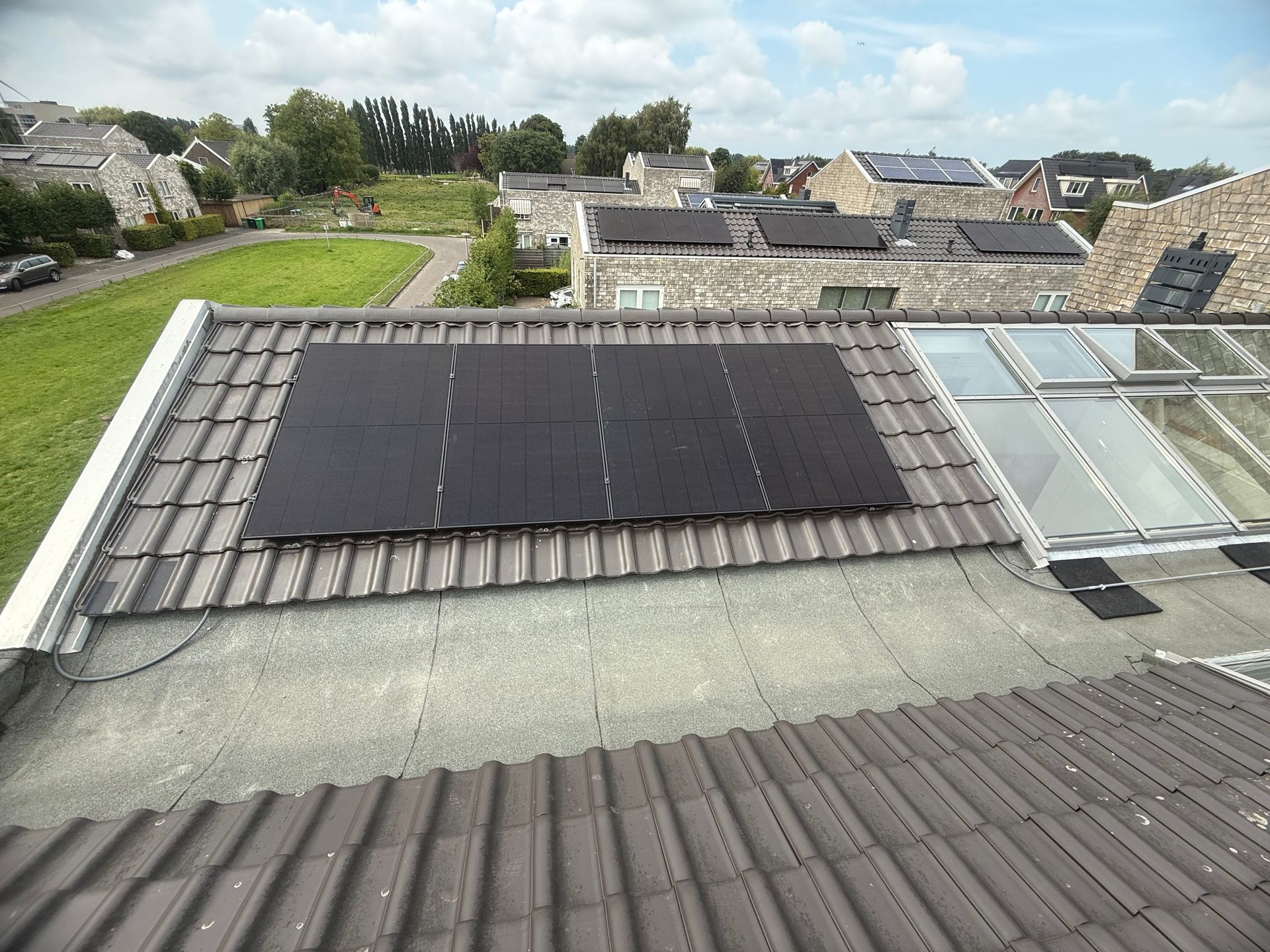 Zonnepanelen op een pannendak met dakramen, in een woonwijk.