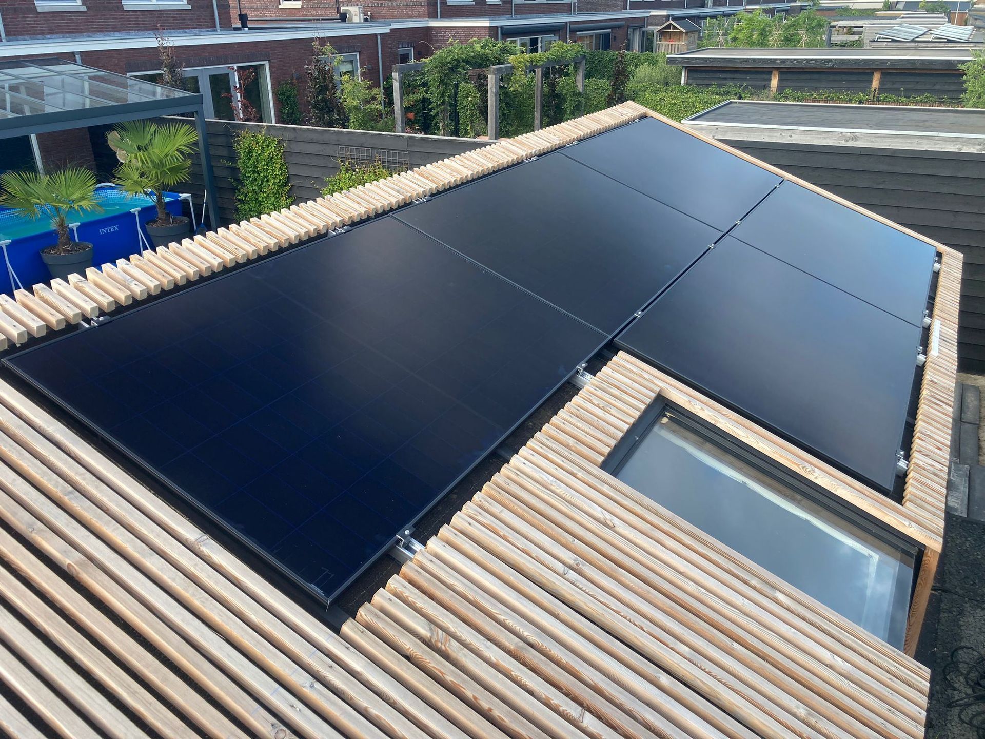 Zonnepanelen op een houten dakconstructie, gemonteerd boven een klein raam.