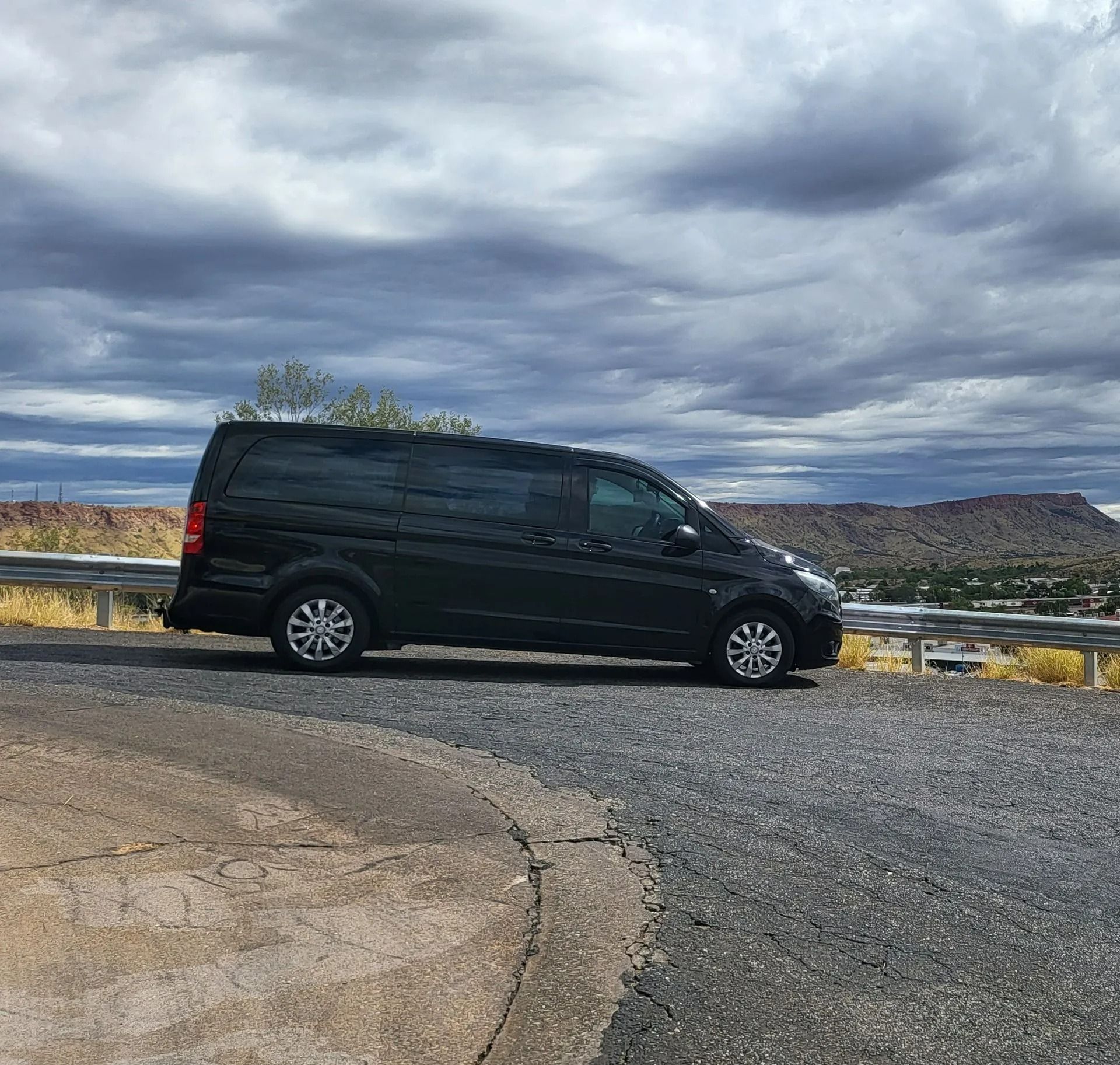 Black van parked on a gravel turnout overlooking a canyon under cloudy skies — ASP Private Hire in Ross, NT