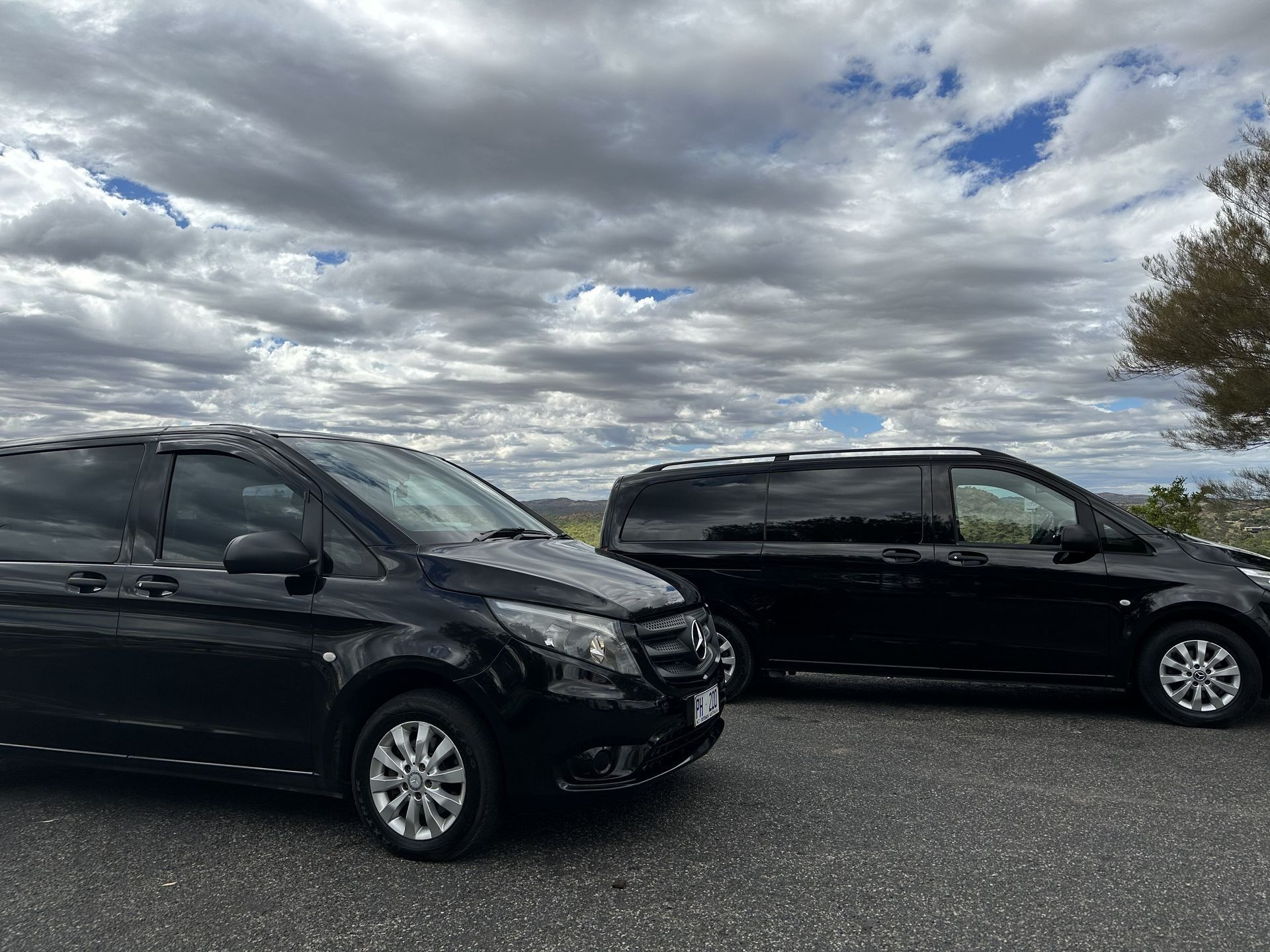 Two black vans parked side by side under a cloudy sky. — ASP Private Hire in Ross, NT