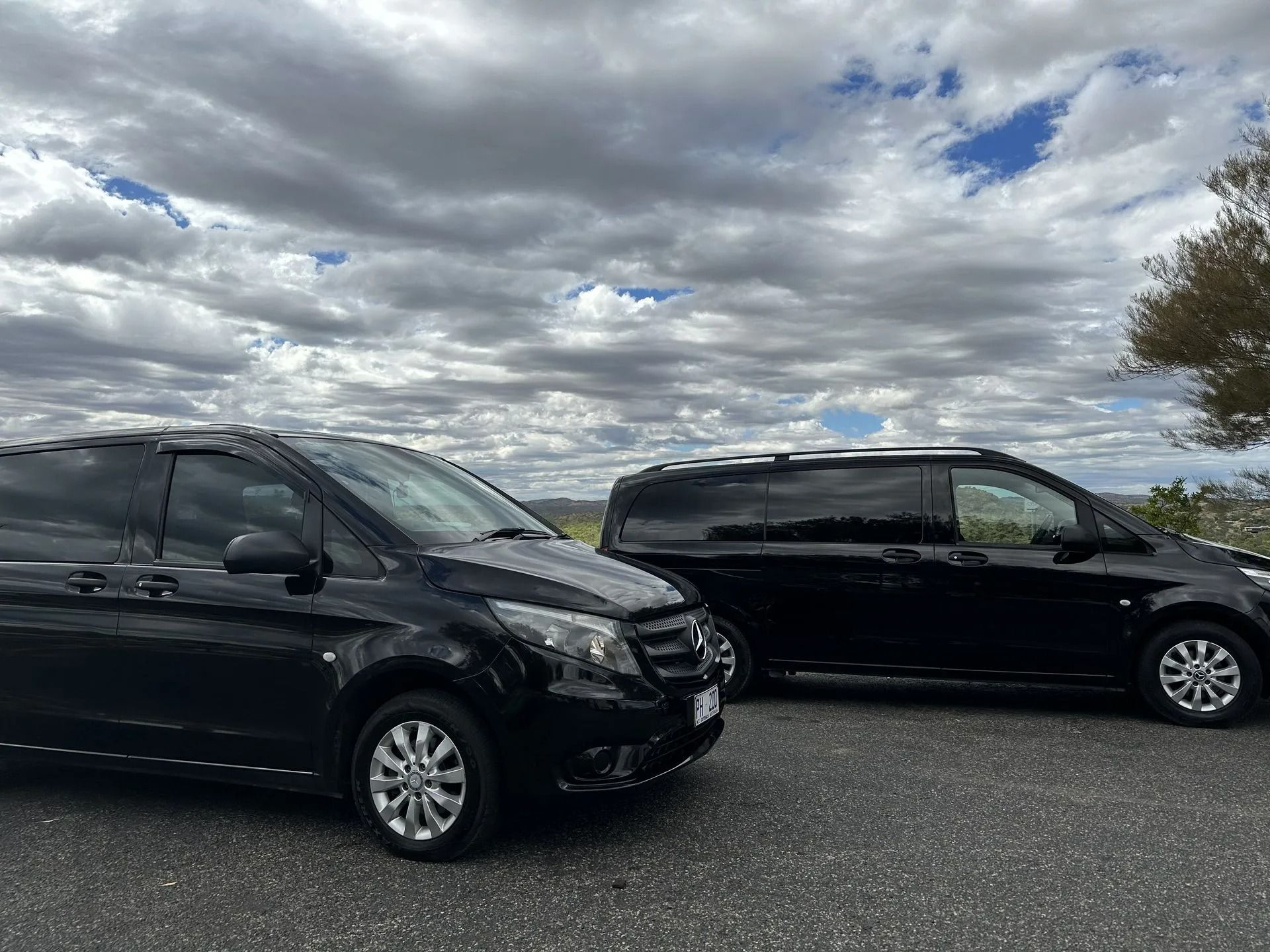 Two black vans parked side by side under a cloudy sky — ASP Private Hire in Ross, NT