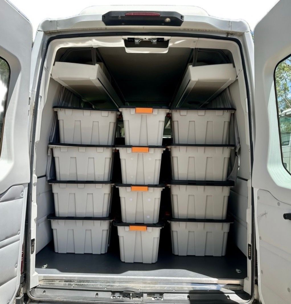 Open cargo van with neatly stacked grey storage bins on shelves inside — ASP Private Hire in Ross, NT