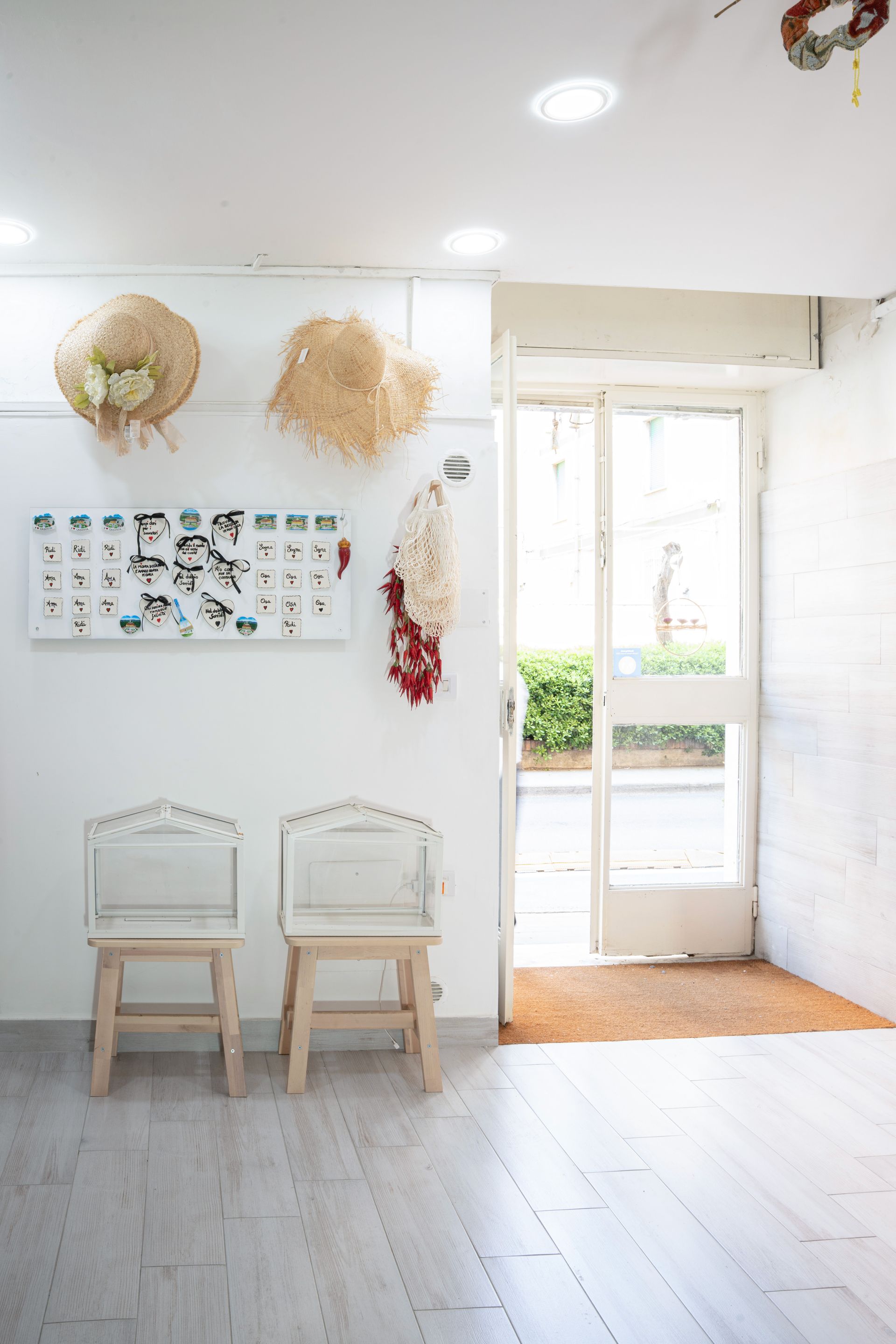 Luminosa stanza minimalista con pareti bianche, due sedie, decorazioni murali e porte finestre che si aprono su un patio soleggiato.