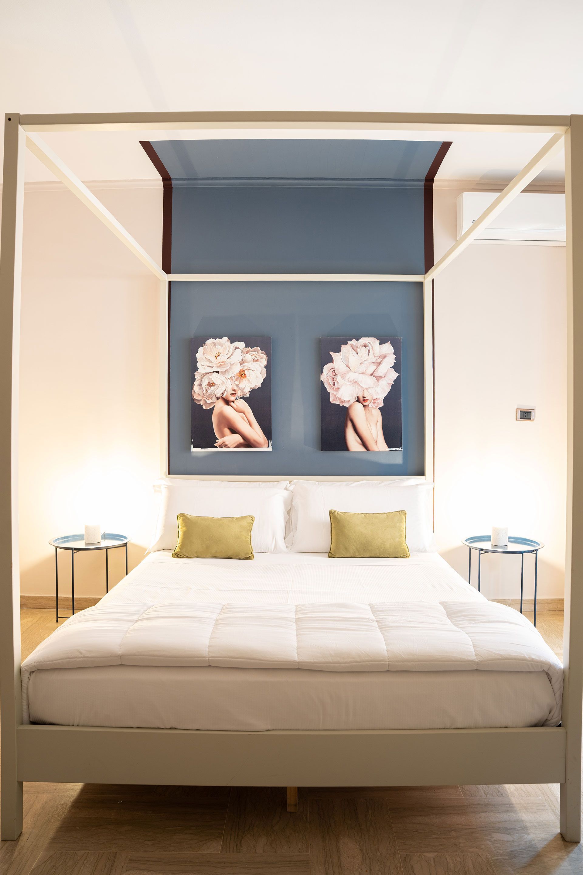 Camera da letto moderna con letto a baldacchino, letto a baldacchino blu e decorazione murale floreale sopra la testiera.