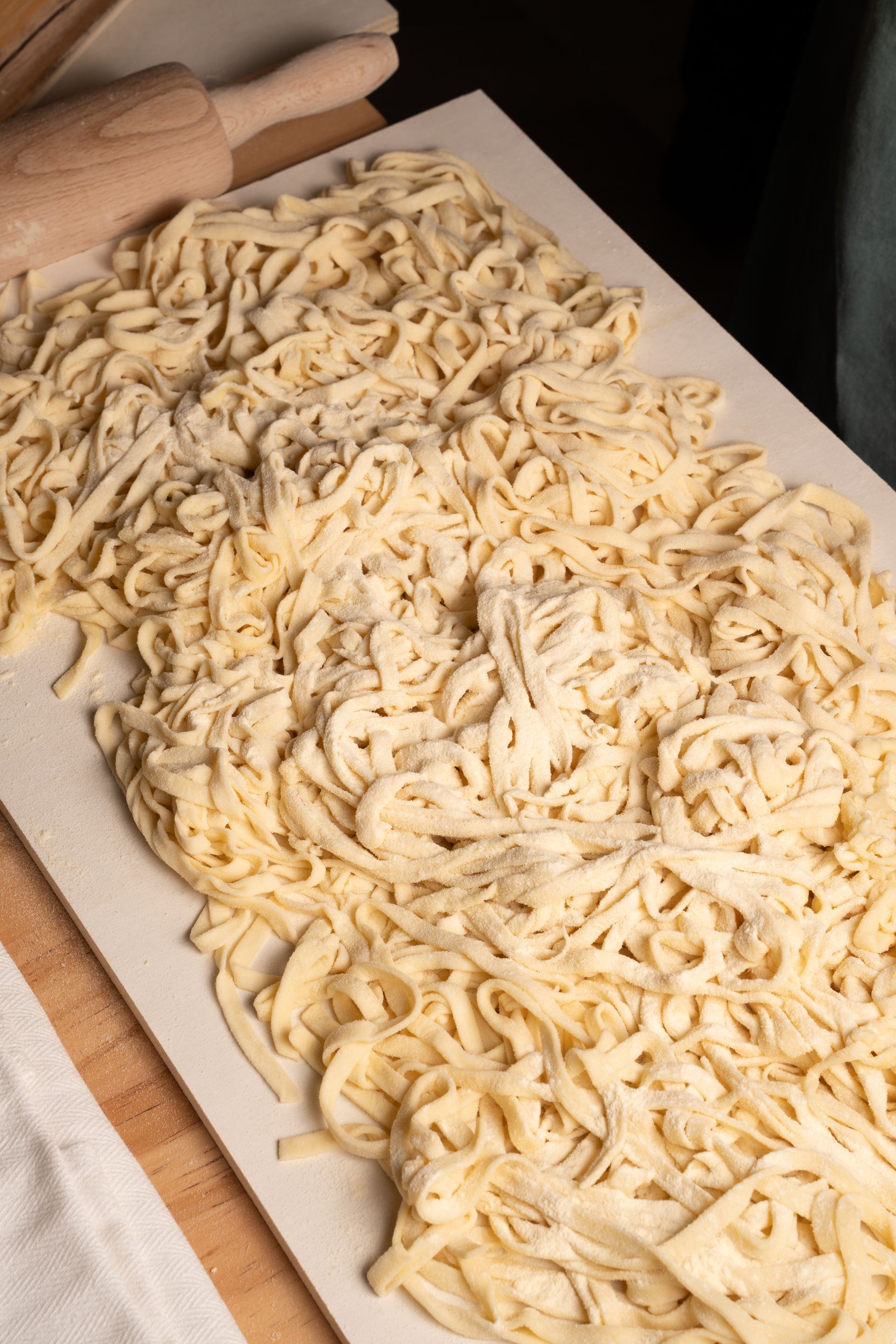 Vassoio di fili di pasta fresca tagliata, disposti su carta da forno.