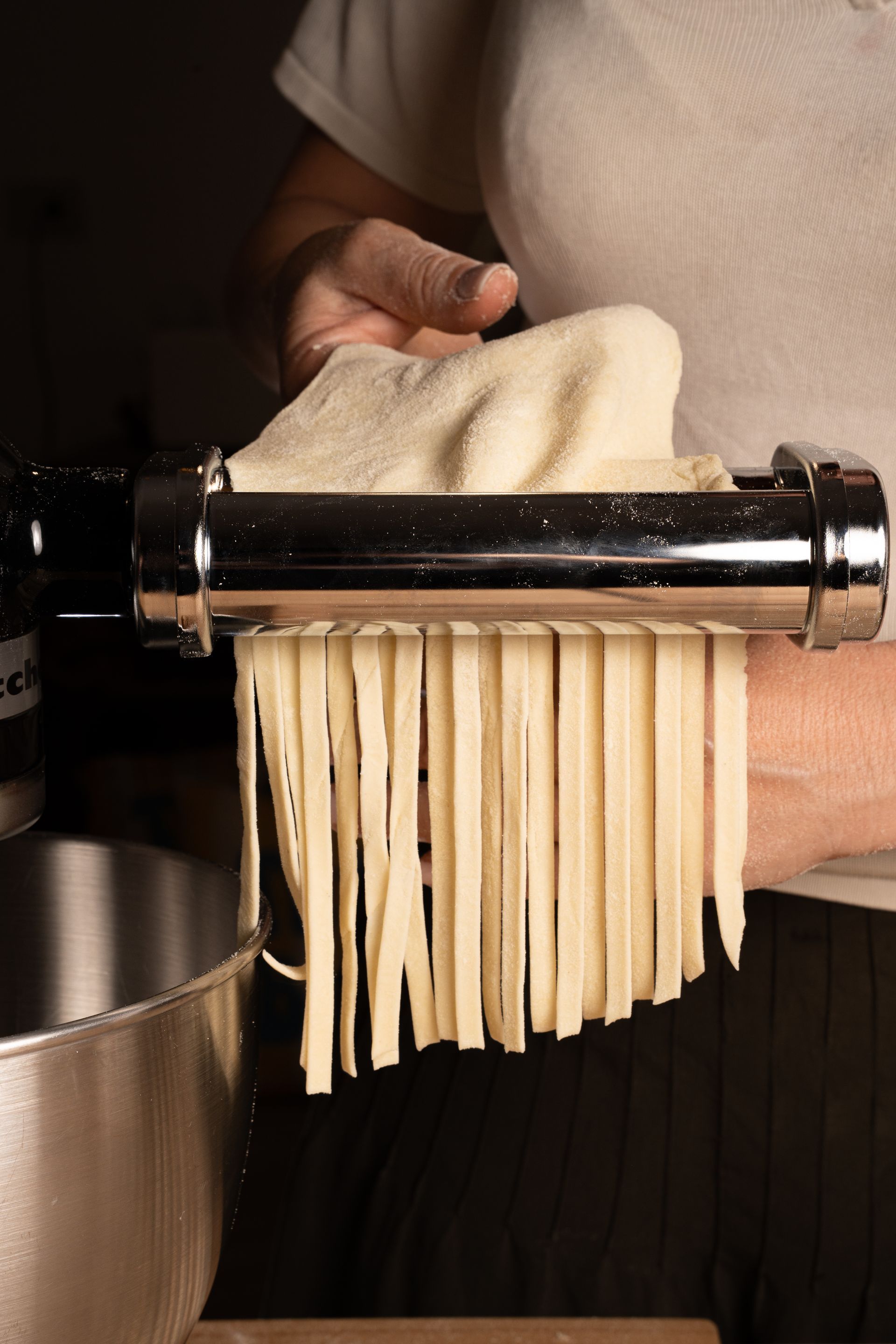 In cucina, fili di pasta vengono fatti passare a mano attraverso una macchina per la pasta.