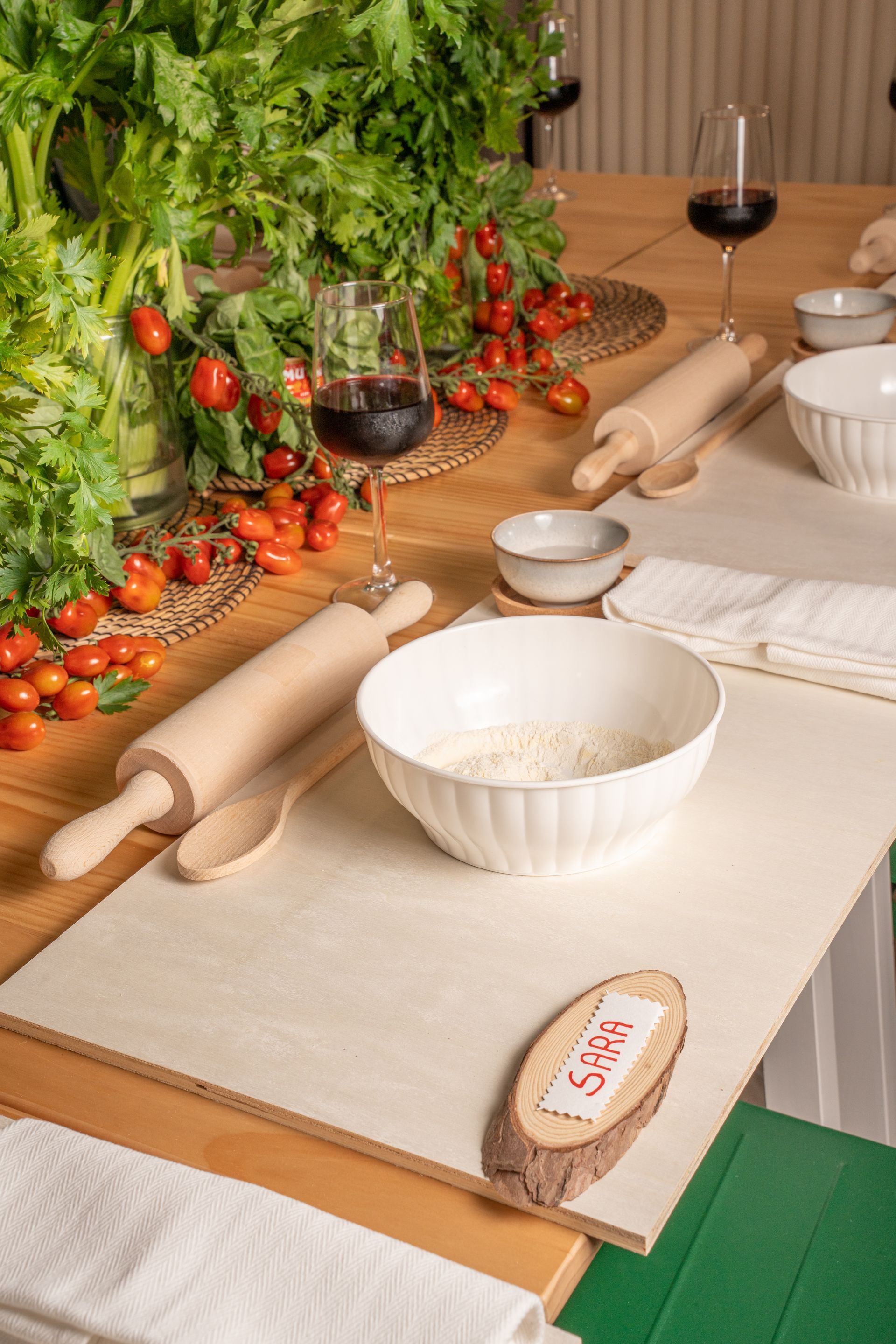 Apparecchiate la tavola con pasta, pane, vino, pomodori e basilico fresco, in un'atmosfera rustica.