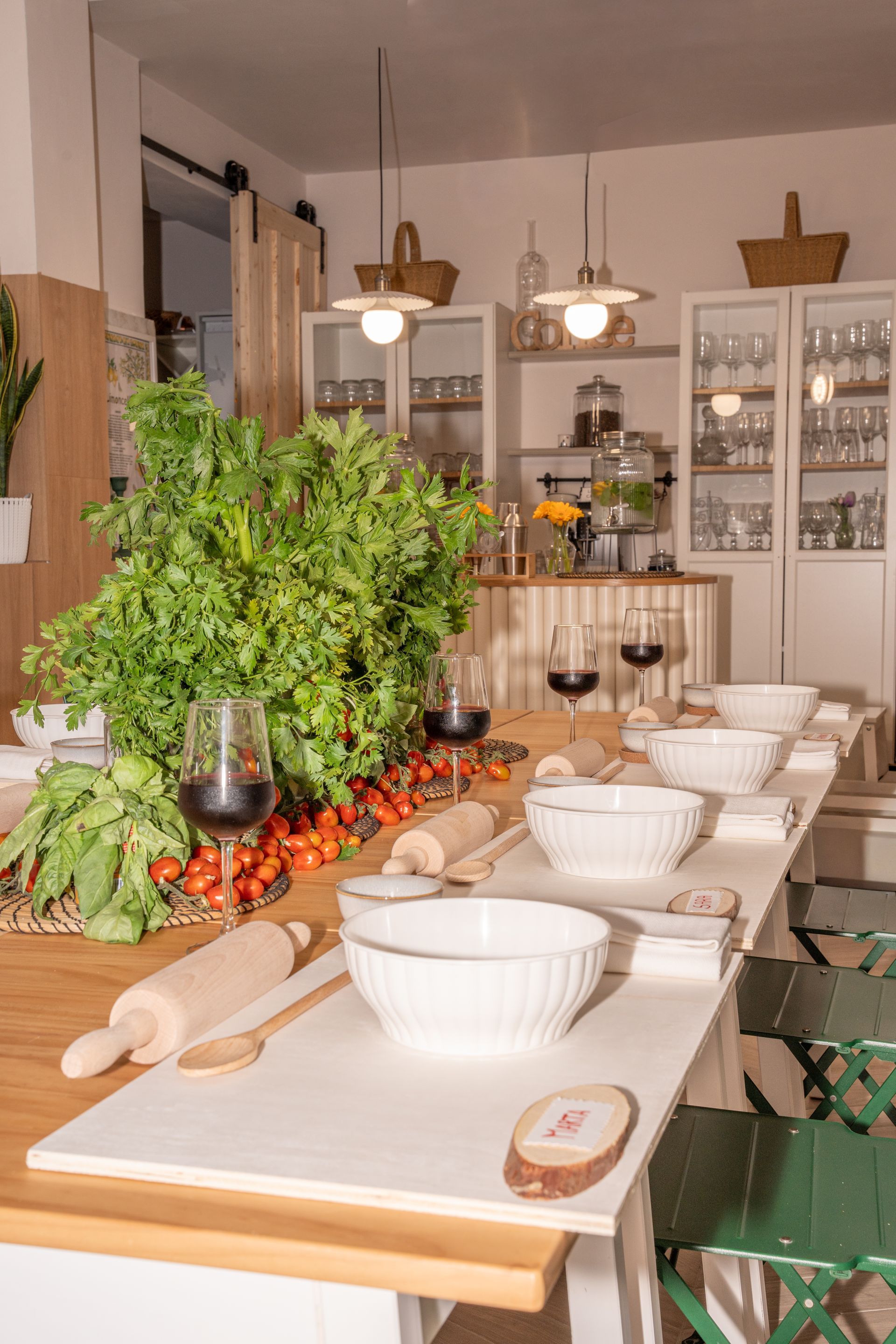 Apparecchia la tavola in una cucina accogliente con ciotole, candele e una grande composizione di erbe aromatiche.