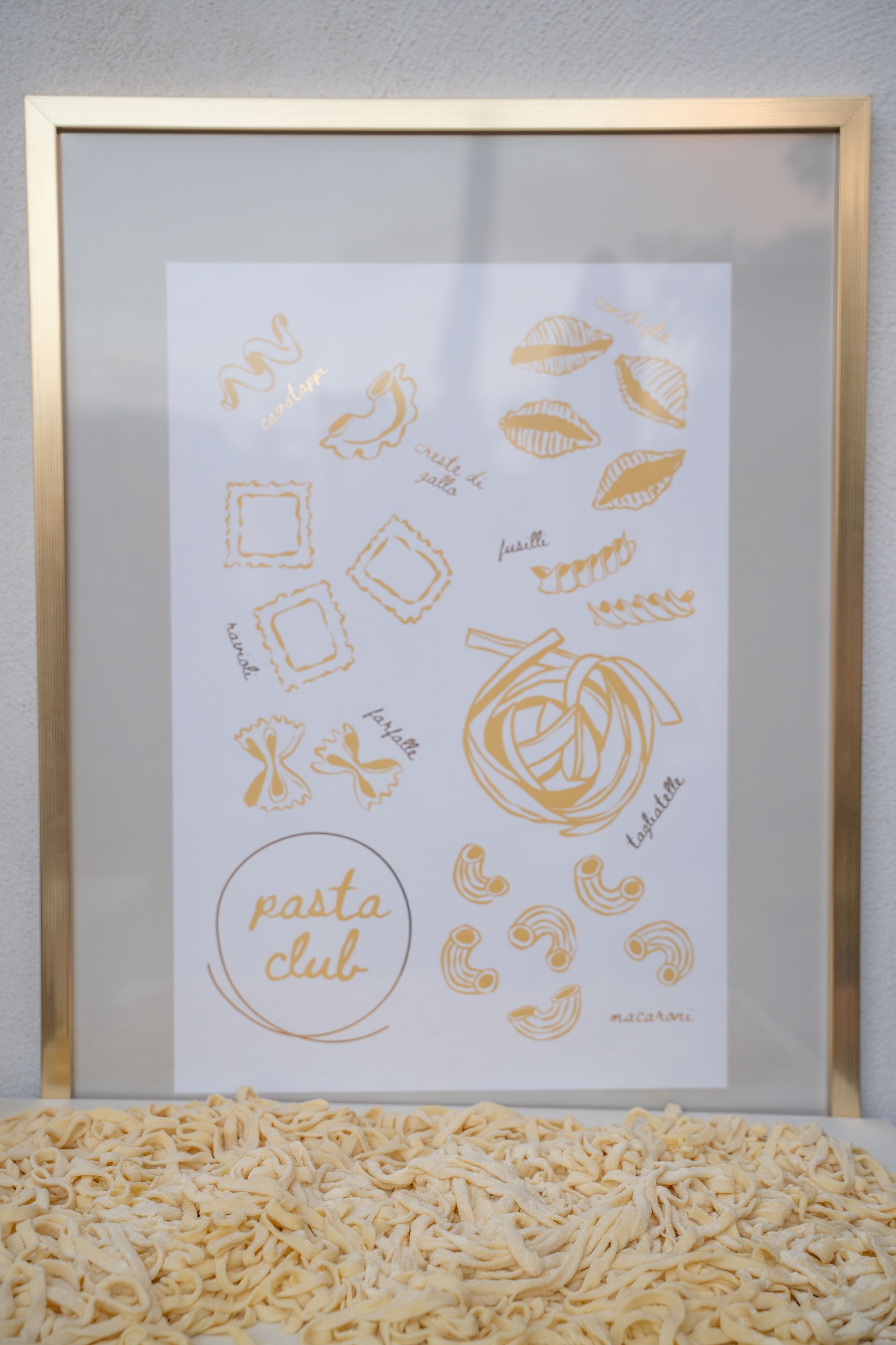 Dettagli dorati sull'invito di nozze, stampati su carta bianca e incorniciati in oro, con anelli e piccoli elementi floreali.