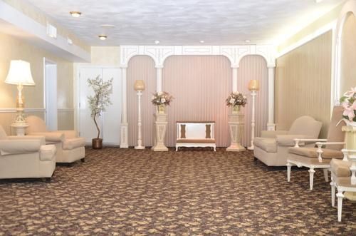 Elegant pastel lounge with beige sofas, floral decor, and a patterned carpet around a central wall display