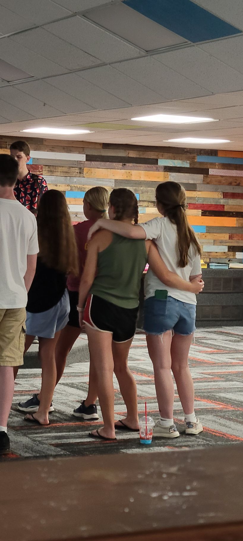 Group of people standing together in a lobby with colorful wall panels and tiled floor