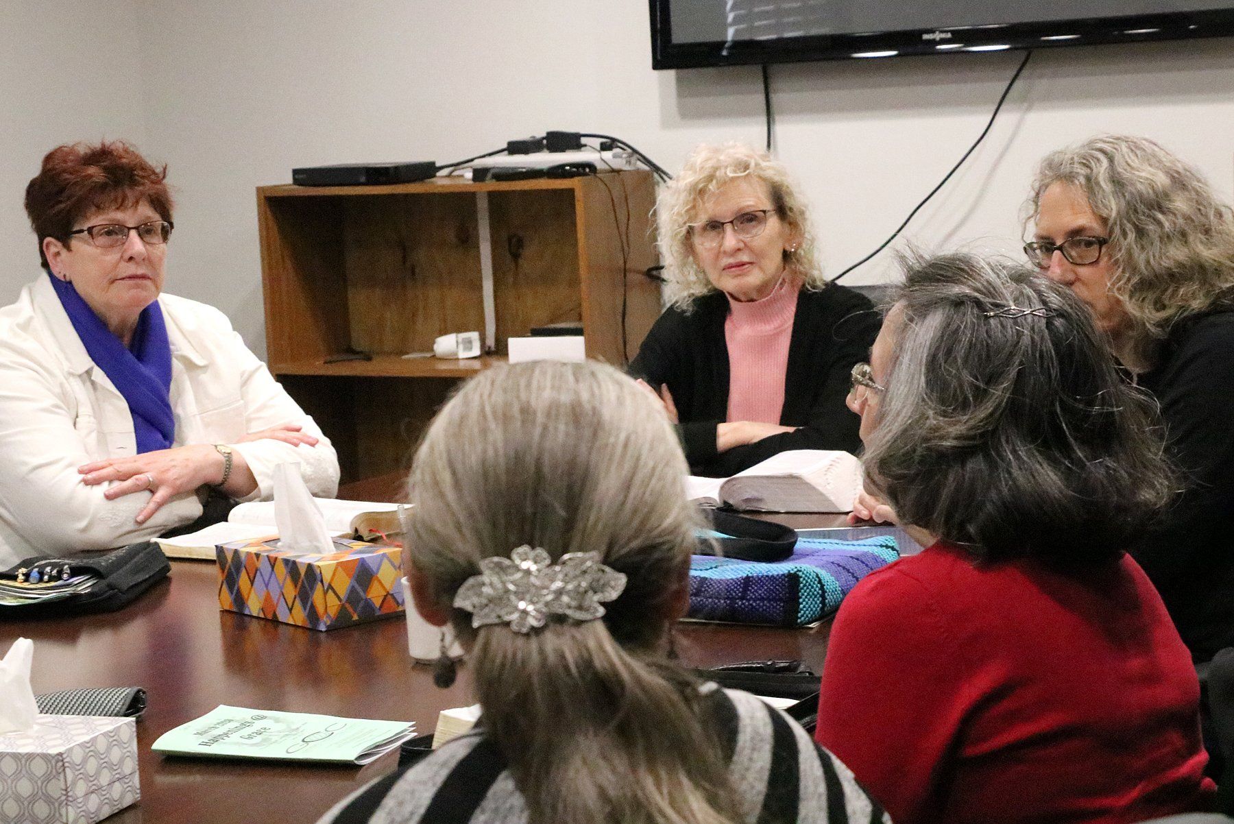 A group of women are sitting around a table having a meeting.