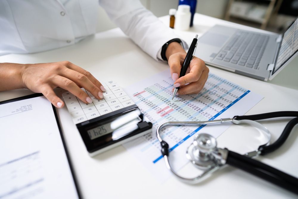 A doctor is using a calculator and writing on a piece of paper.