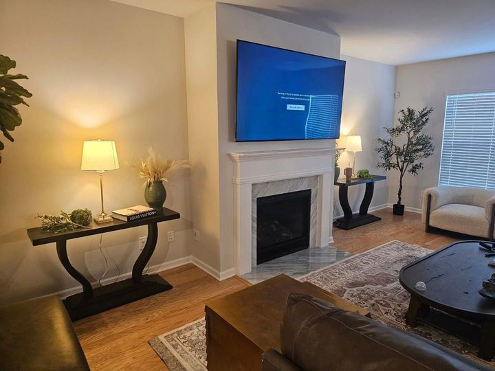 Living room with fireplace, wall-mounted TV, lamps, and brown leather furniture