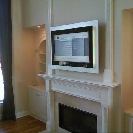 White fireplace with a flat-screen TV mounted above it in a beige living room.