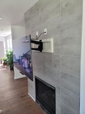 Wall-mounted TV on a gray tiled fireplace wall in a modern living room