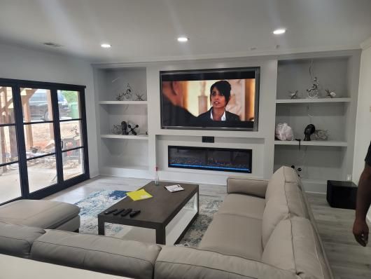 Modern living room with sectional sofa, coffee table, built-in shelves, and wall-mounted TV