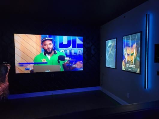 Dark TV studio with a man on screen and two framed displays on a blue-lit wall