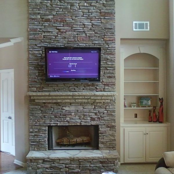 Living room stone fireplace with wall-mounted TV and built-in shelving on the right