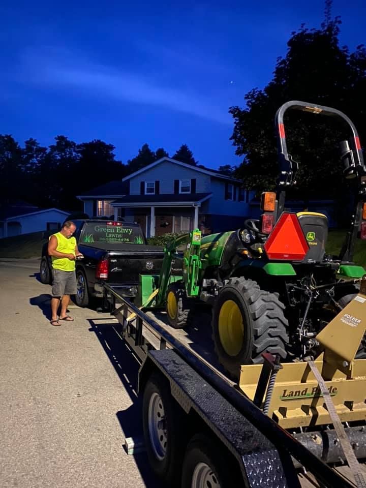 A man is standing next to a john deere tractor on a trailer