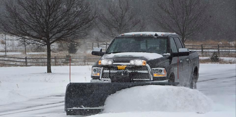 A truck is plowing snow on a snowy road.