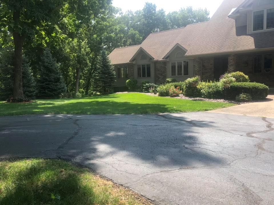 A large house with a lush green lawn and a driveway in front of it.