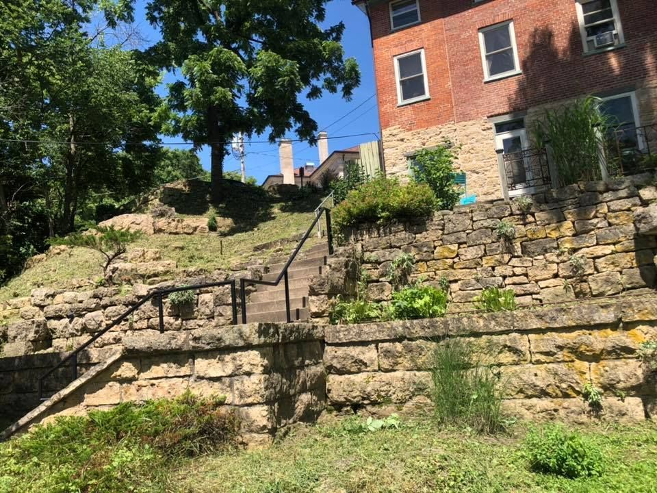 A stone wall with stairs leading up to a brick building.