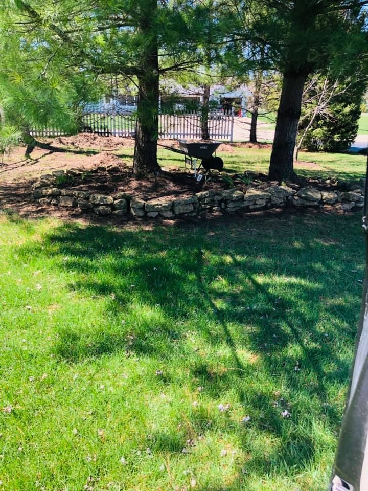 A lush green lawn with trees and rocks in the background.