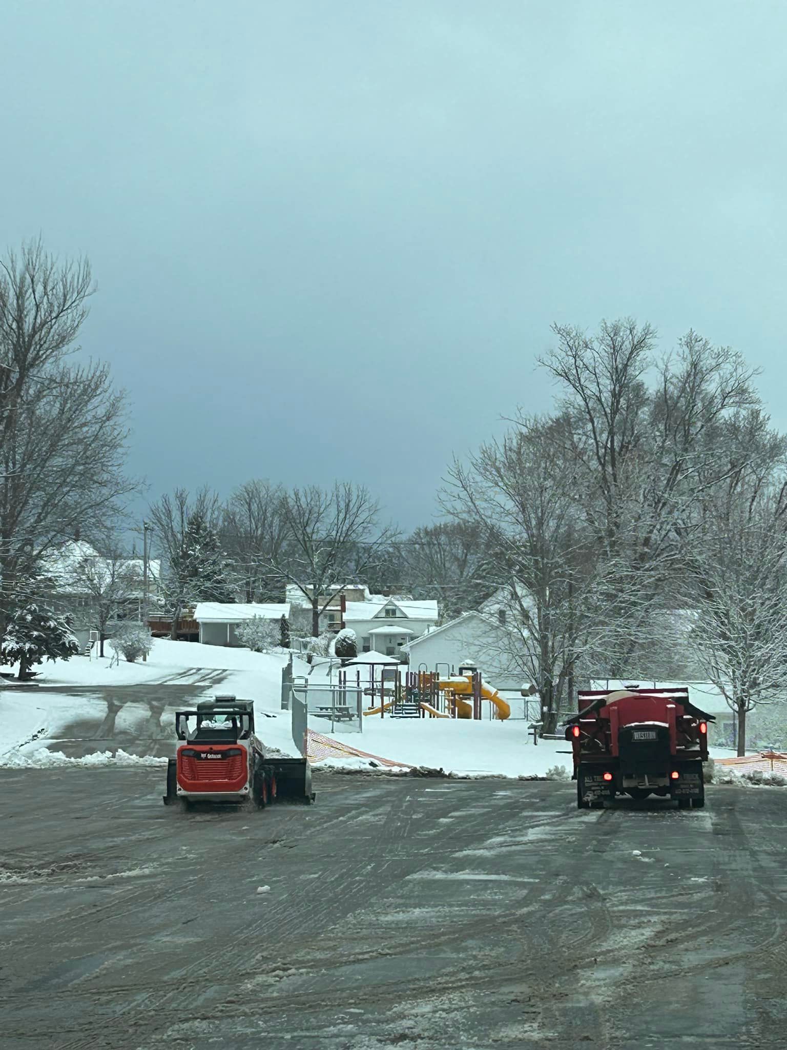 A couple of trucks are parked in a parking lot in the snow.