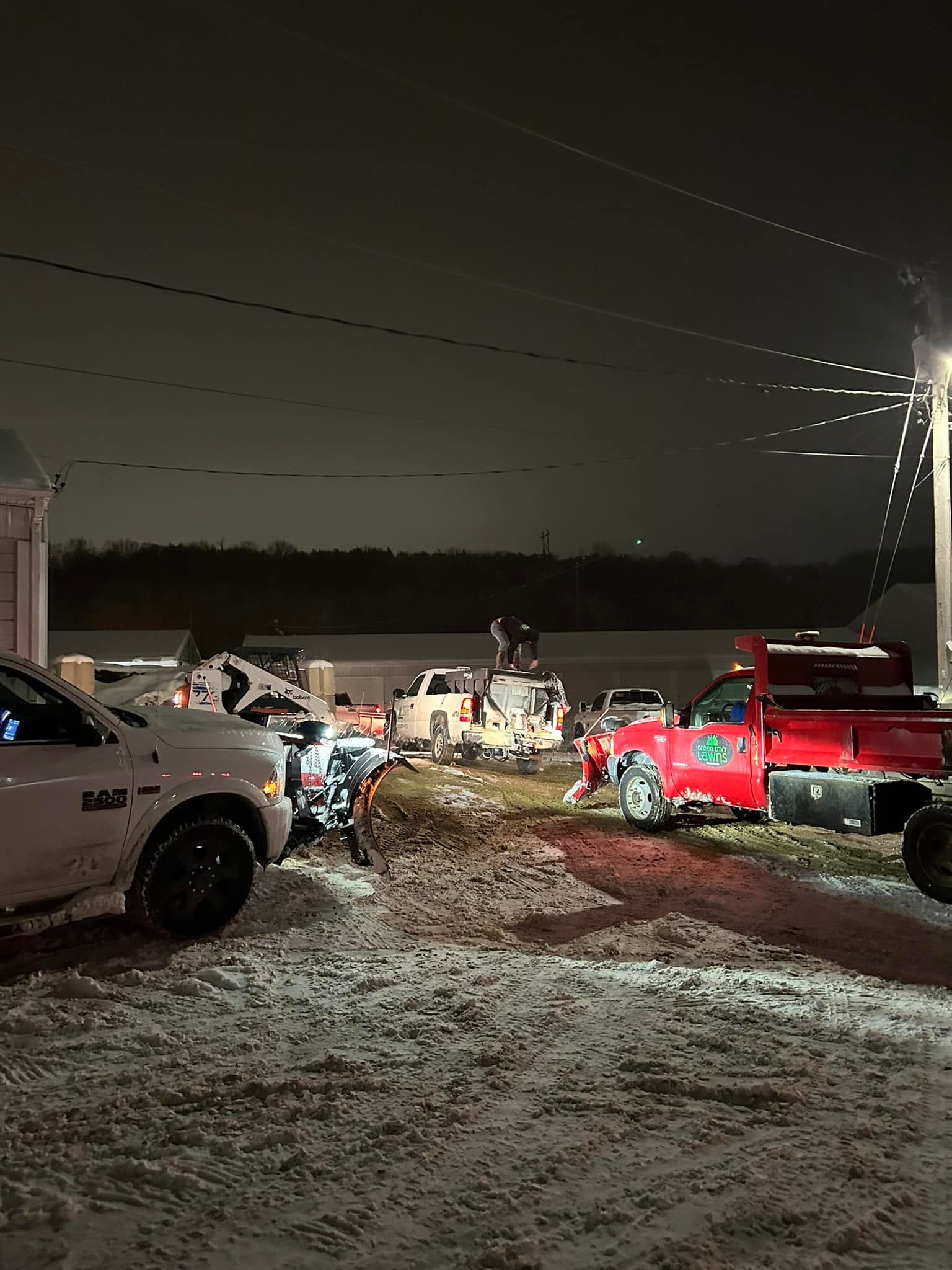 A lot of trucks are parked in the snow at night.