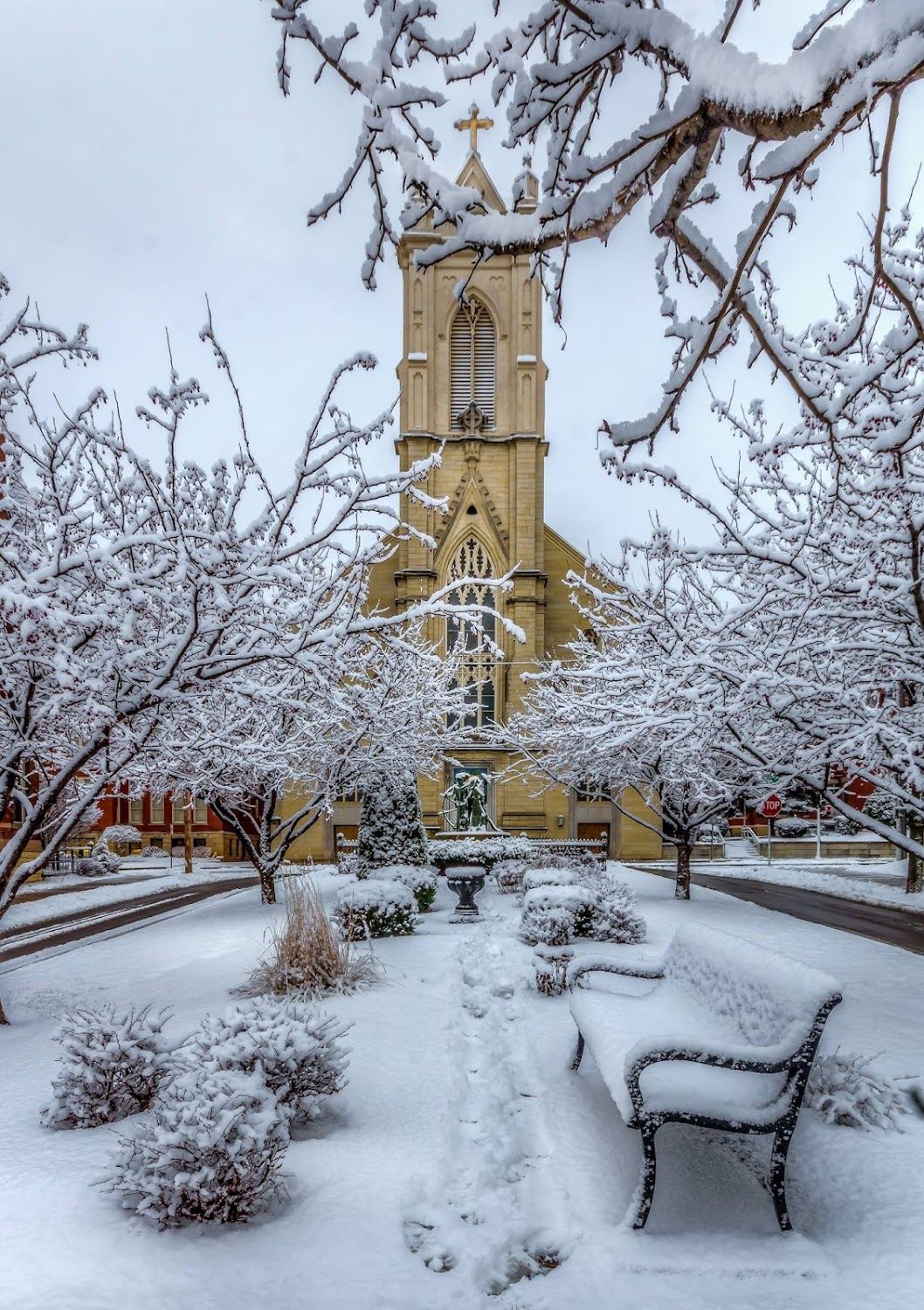 A church covered in snow with a bench in front of it