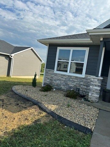 A house with a lot of windows and gravel in front of it.