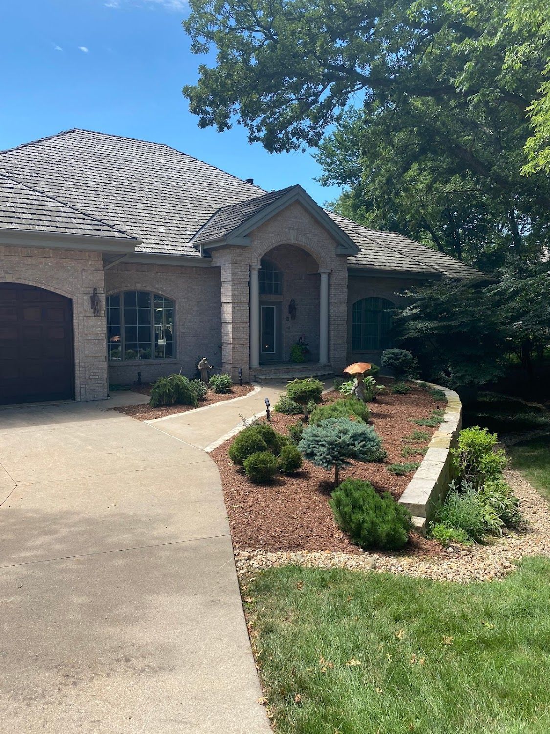 A large brick house with a gray roof and a driveway leading to it.