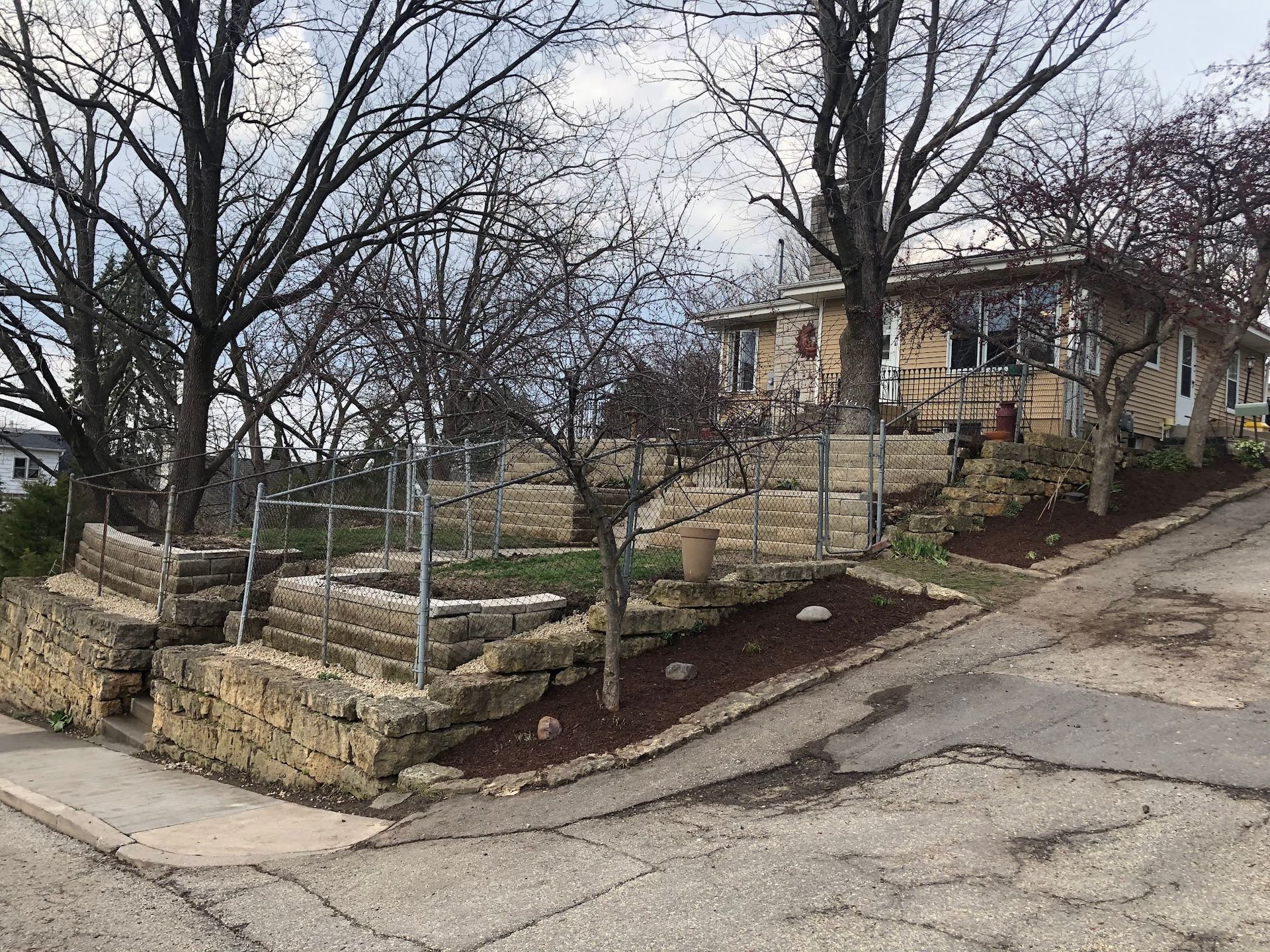 A house is sitting on the corner of a hill next to a stone wall.