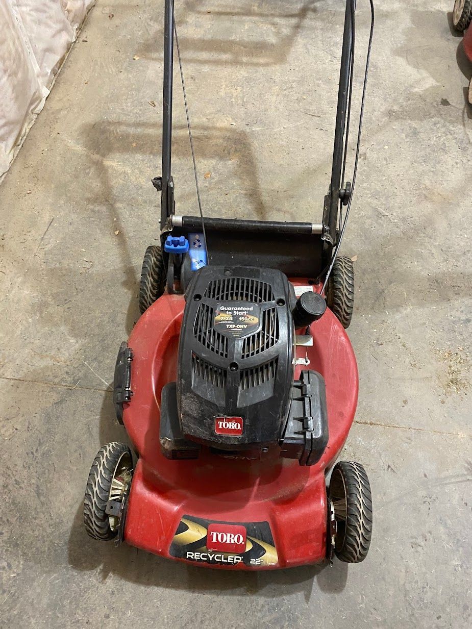 A red lawn mower is sitting on the ground in a garage.