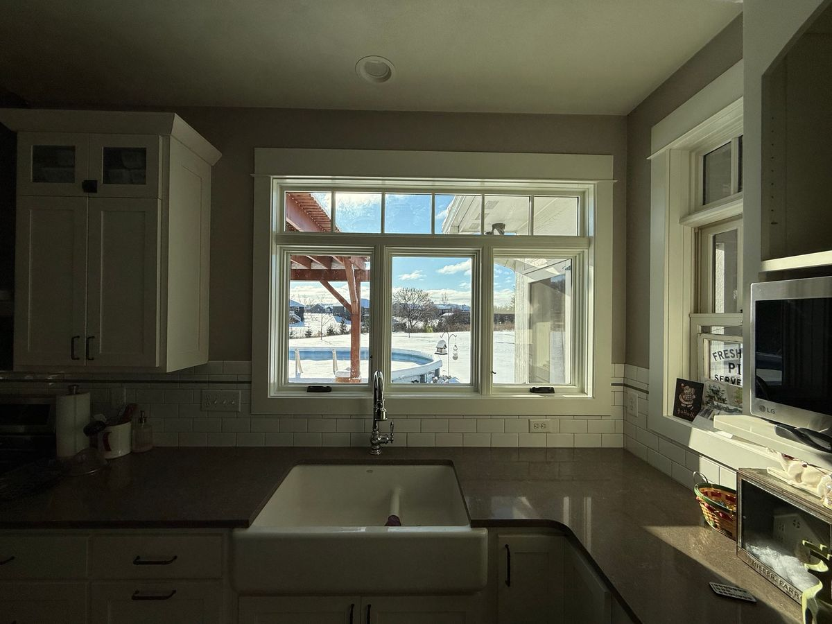 A kitchen with a sink and a window with a view of a snowy mountain.