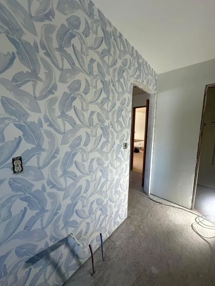 A hallway with a ladder on the floor and a wall with a pattern on it.