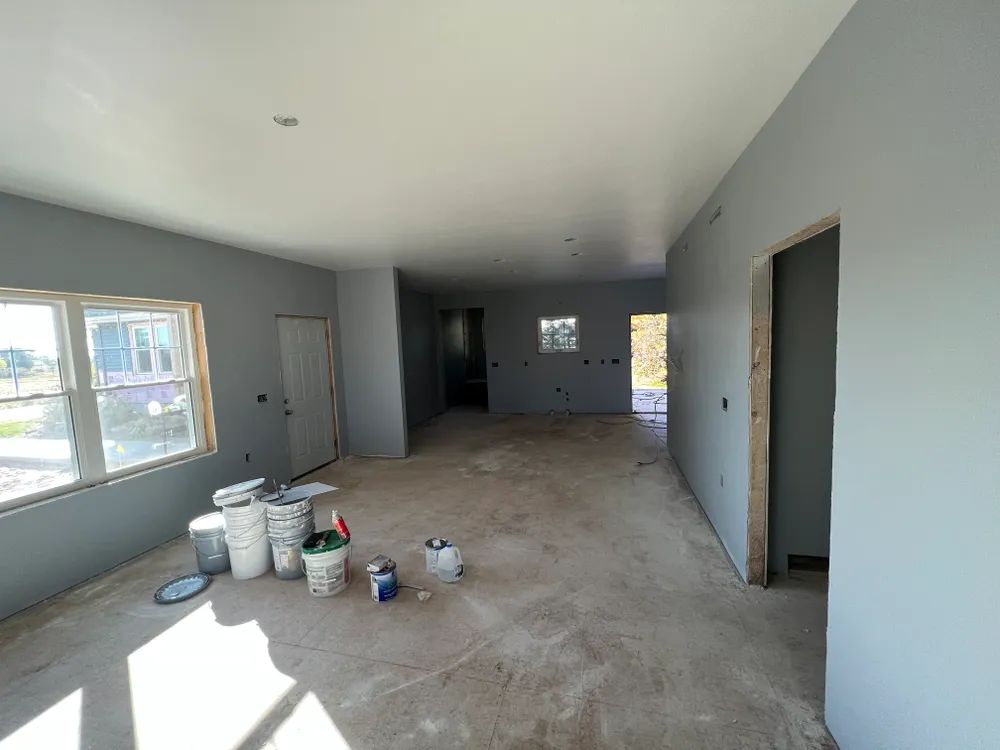 An empty room with buckets of paint on the floor.