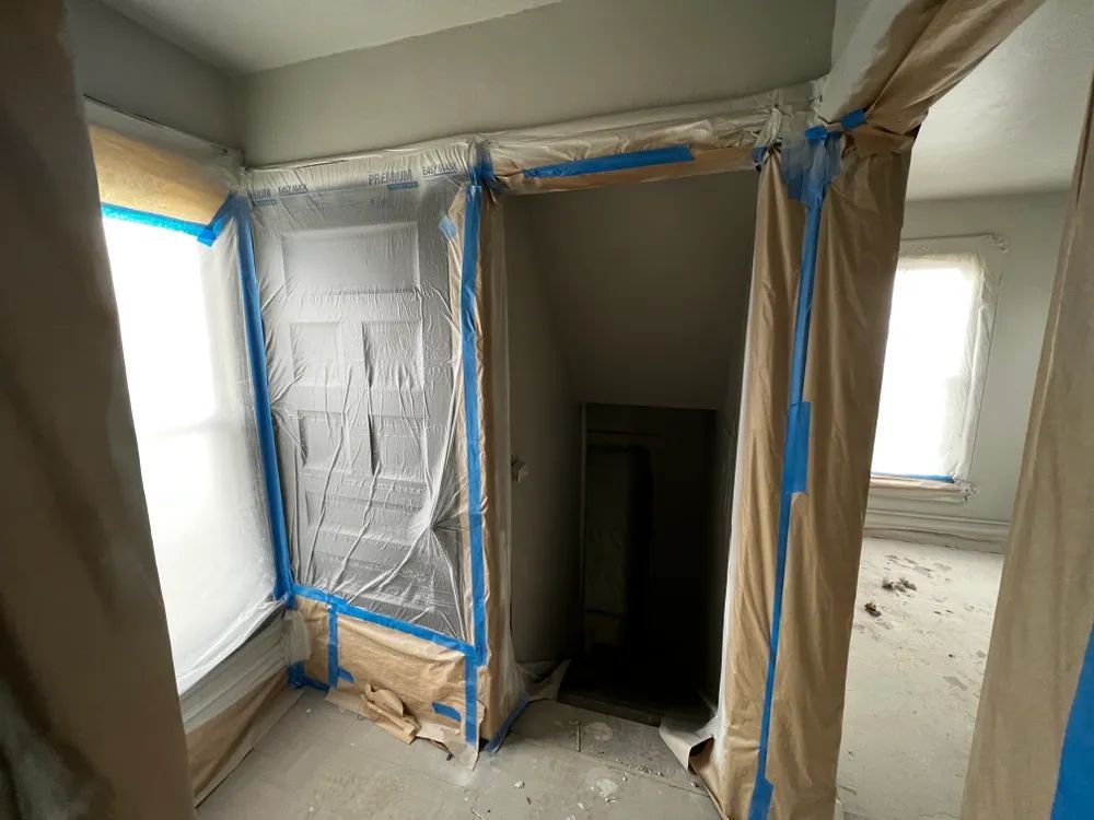 A room with a fireplace and a door covered in plastic.
