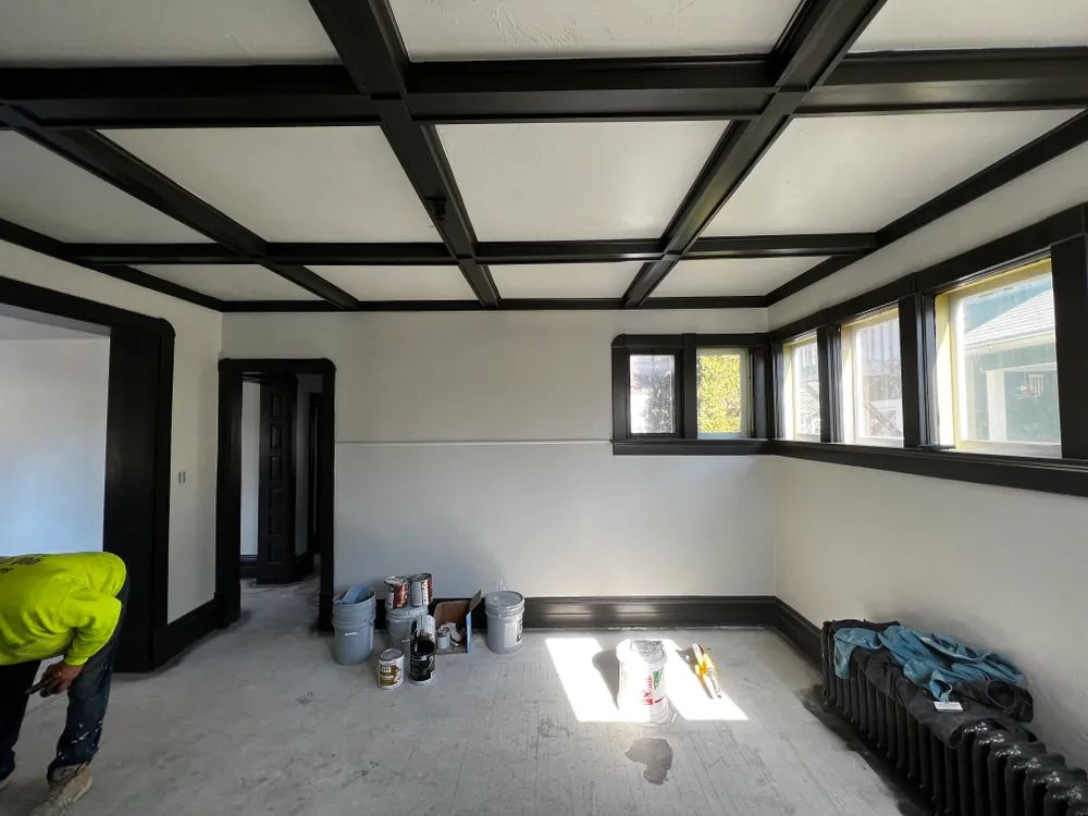 A man in a yellow hard hat is working in an empty room
