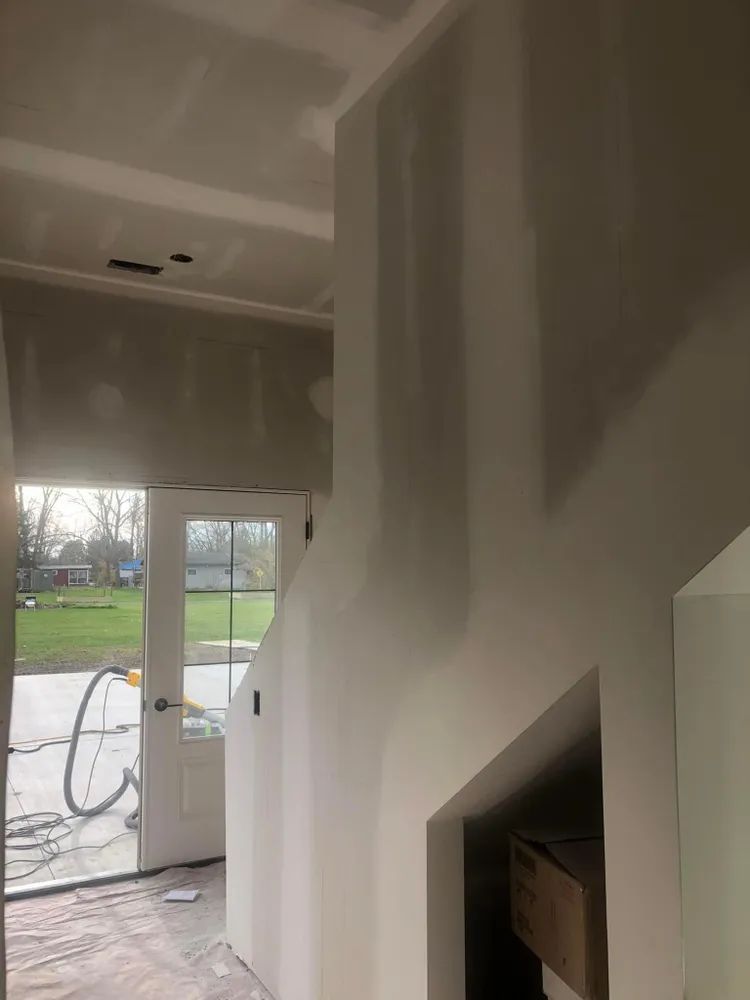 A hallway with a door and stairs in a house under construction.