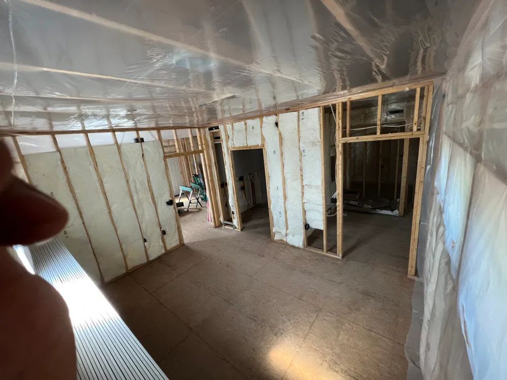 A person is standing in a room with a lot of insulation on the walls.