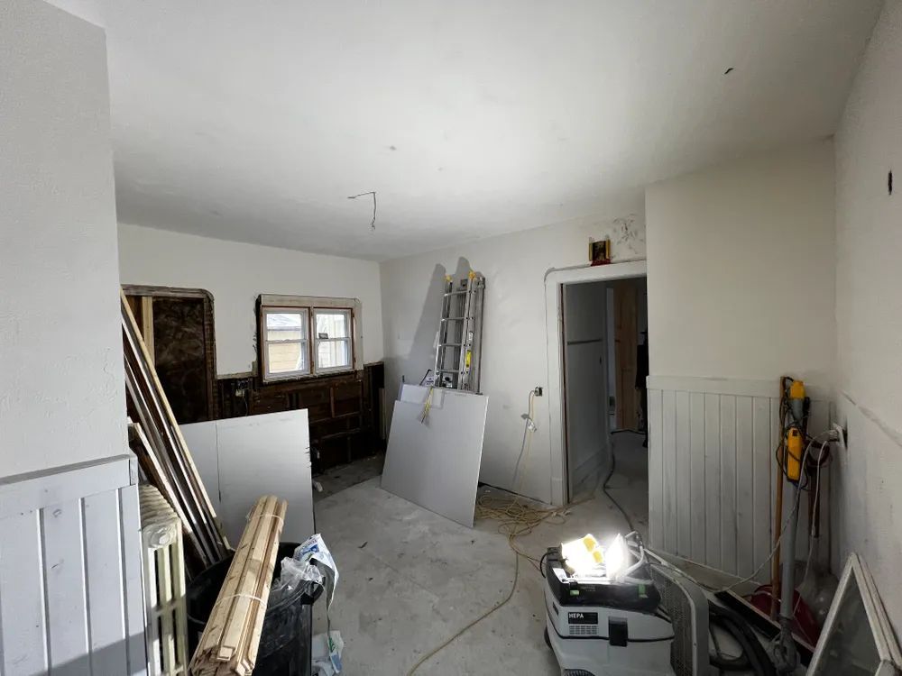 A room with a ladder and a vacuum cleaner in it