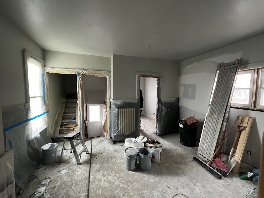 A room with buckets of paint and a ladder in it.