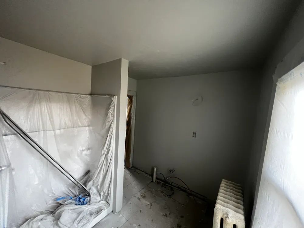An empty room with a radiator and a broom in it.