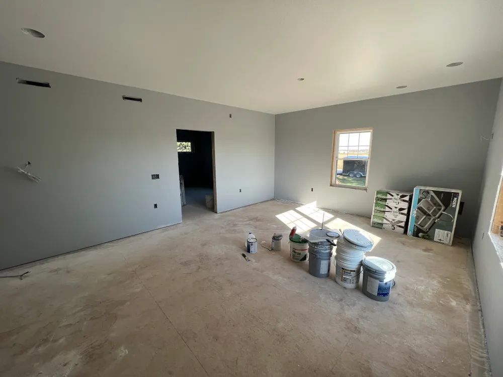 A room with buckets of paint on the floor and a window.