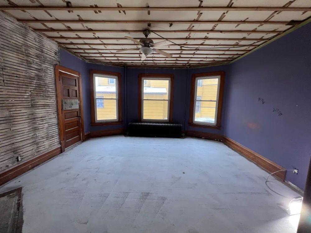 An empty room with purple walls and a ceiling fan