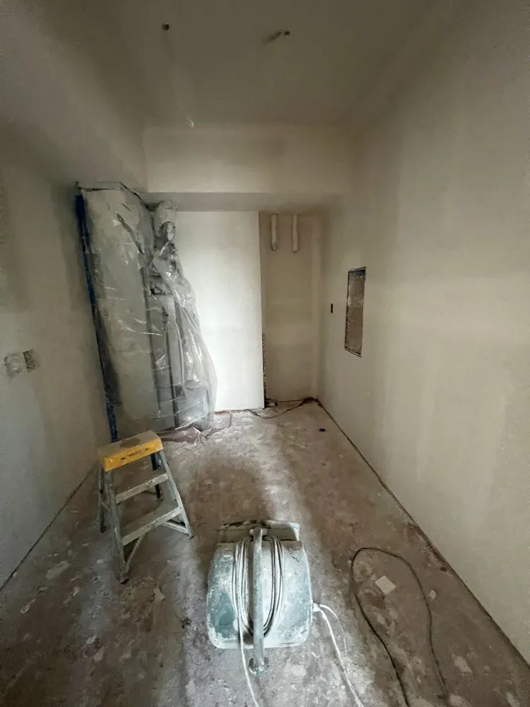 A room with a ladder and a vacuum cleaner in it.