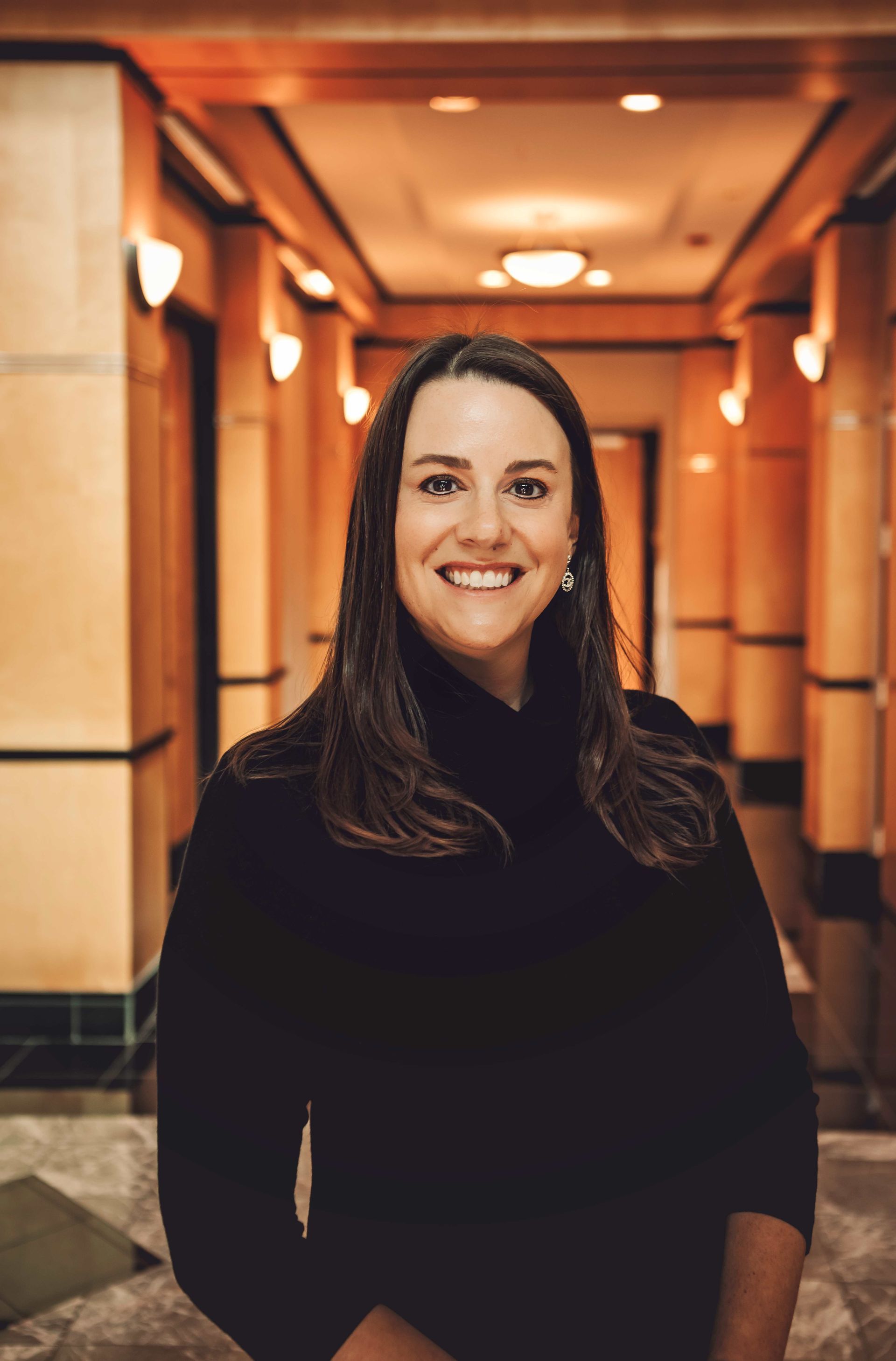 A woman is standing in a hallway smiling for the camera.